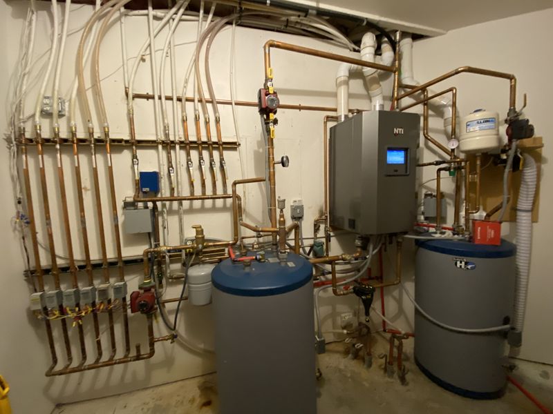 An older model boiler system with storage tanks for domestic hot water and in floor radiant heating