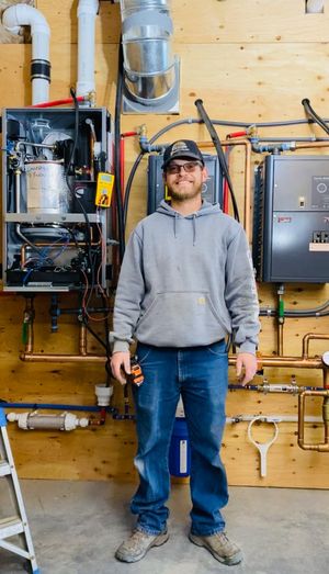 The owner of Radiant 307 Plumbing, Remington, standing in front of a custom boiler and tankless hot water system on a residential project